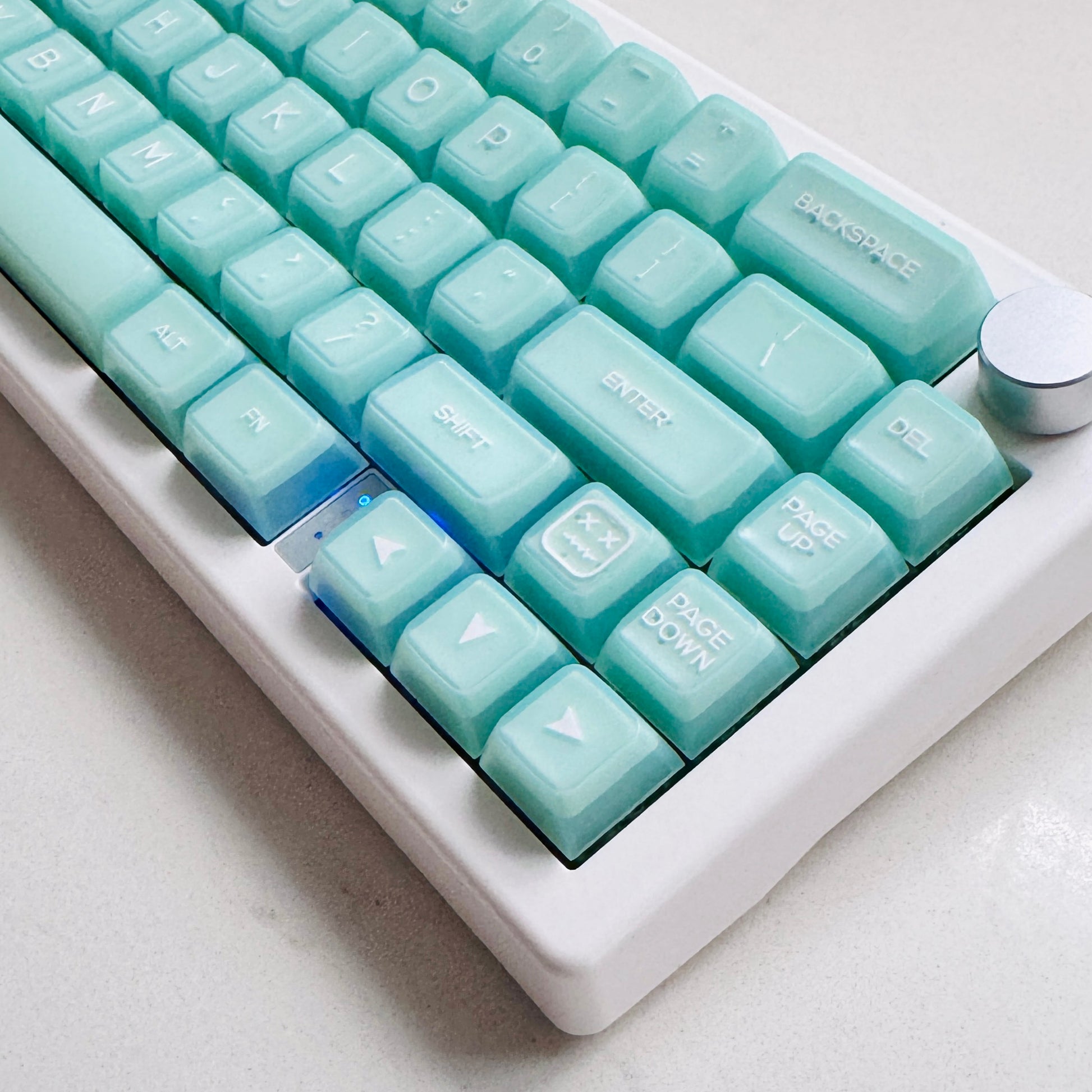 A mechanical keyboard with light mint green keycaps and a wireless RGB frame, displaying various colored lighting patterns.