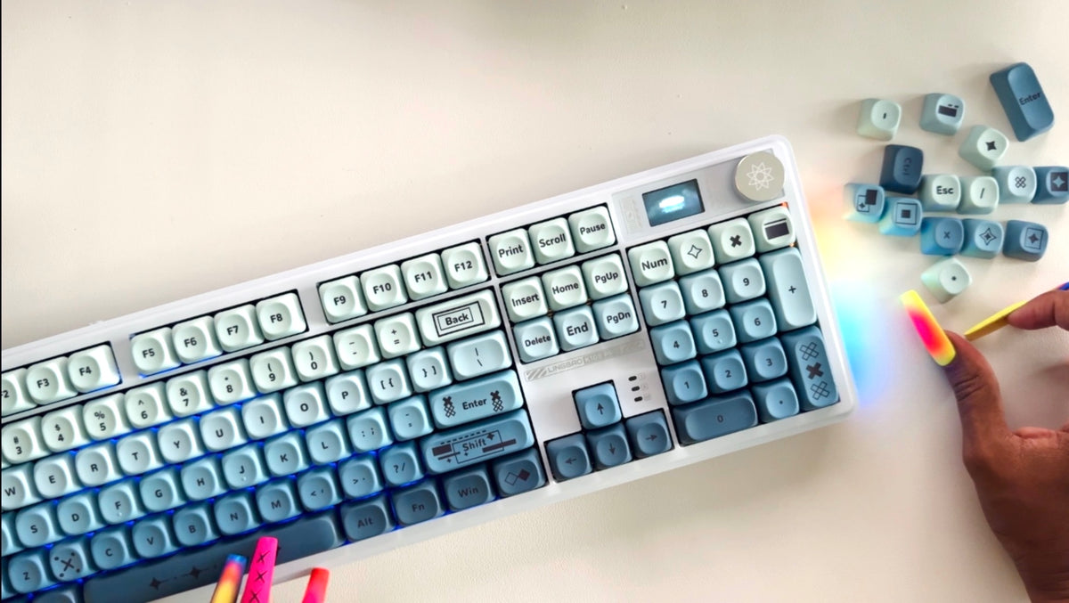 The Siren full-size keyboard in powder blue with RGB backlighting, ice-white-to-deep-ocean gradient keys, typed with long rainbow nails