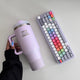 Hand with long nails holding the lilac Keys Open Doors tumbler next to the translucent purple Frost keyboard