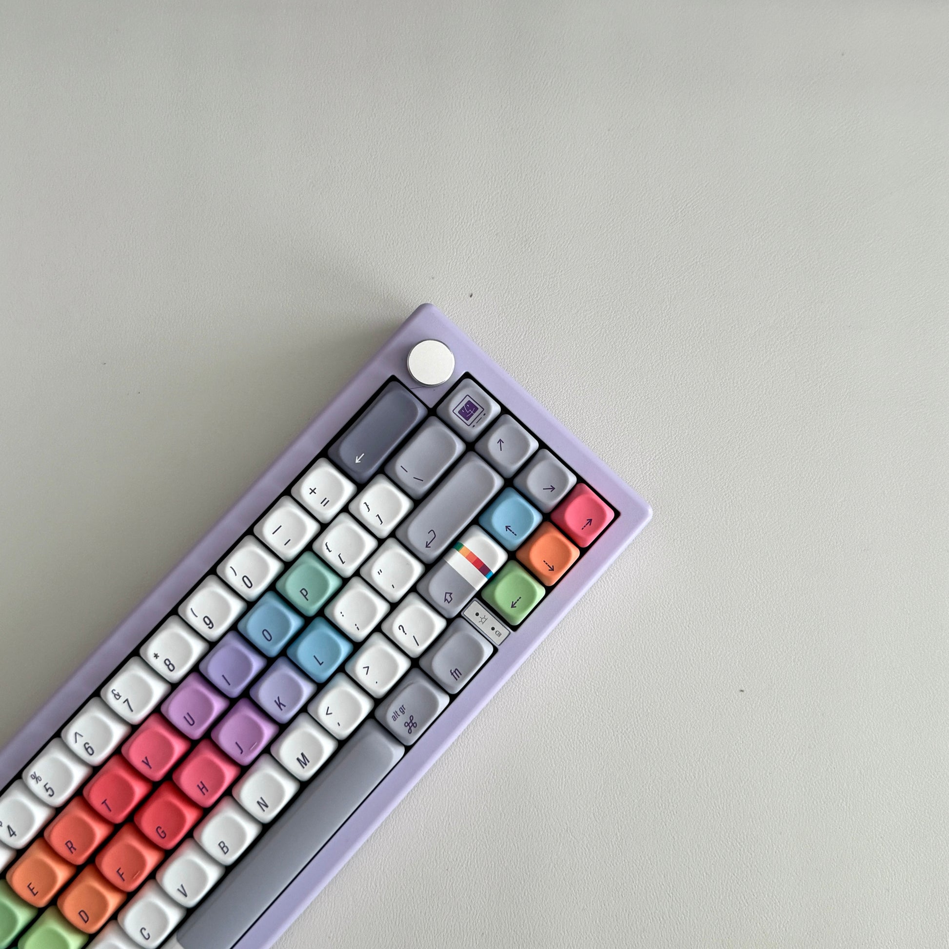 A compact mechanical keyboard for Mac with a pastel lavender-purple frame and multicolor keycaps arranged in a rainbow gradient - this is The Retro Finder by Claw x Code for long nails