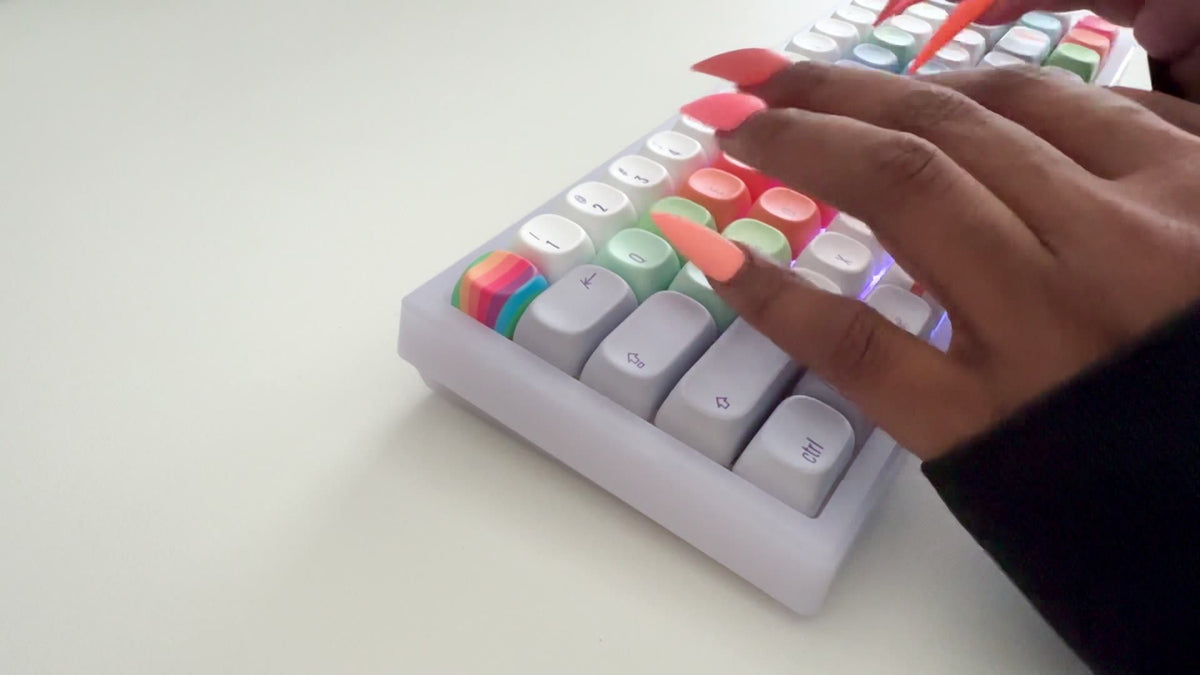 Long coral nails typing on The Retro Finder keyboard, the translucent Frost frame glowing under pastel rainbow keys